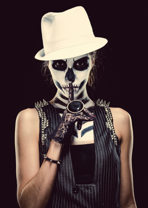 Woman with skeleton face art making a hush gesture