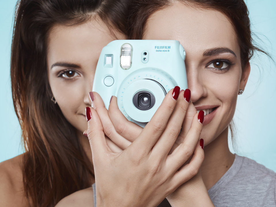 Studio lifestyle portrait of two best friends hipster crazy girls with polaroid wearing stylish bright outfits