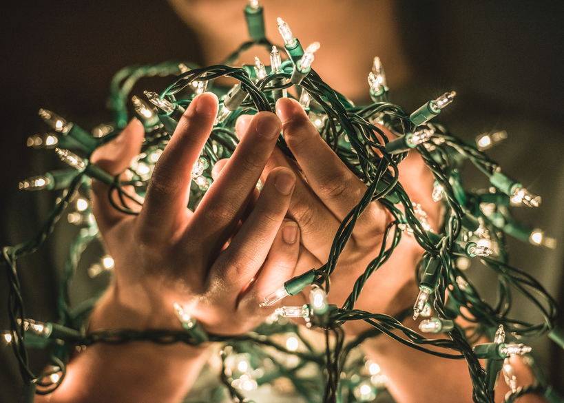 Hands holding glowing string of white Christmas lights